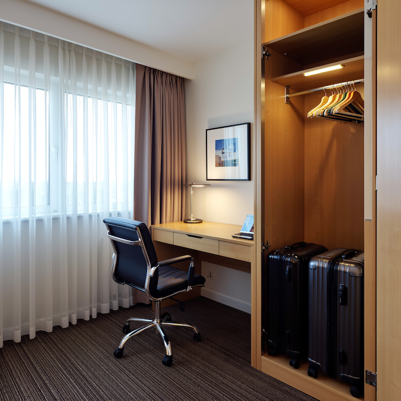 Praktický pracovní kout a skříň v hotelovém pokoji